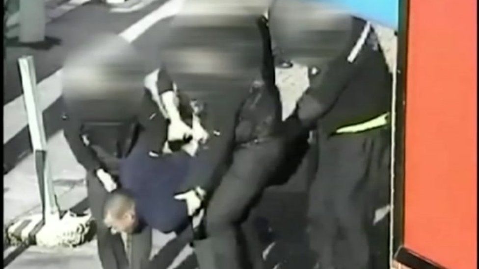 Leon Briggs being carried by police officers to police van