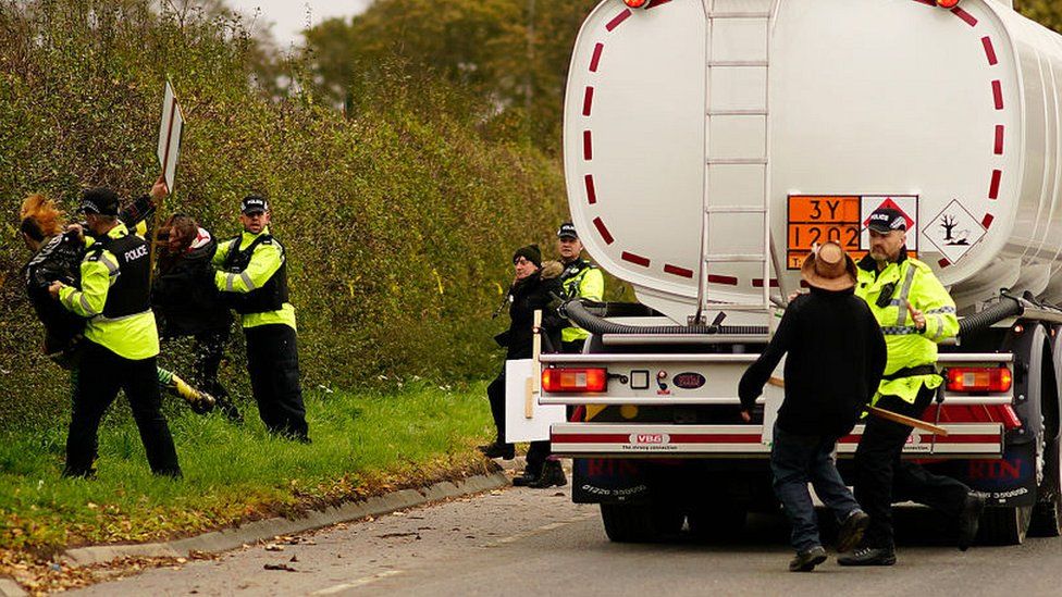 Police officers restrain an anti-fracking protester attempting to stop a tanker lorry leaving the Preston New Road
