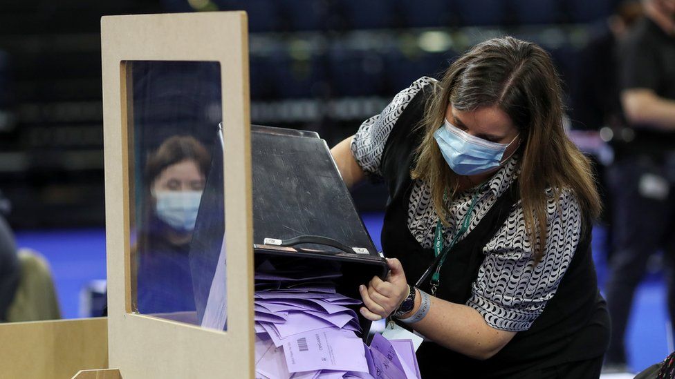 A staff member empties lilac ballot papers from the ballot box at a count in Glasgow