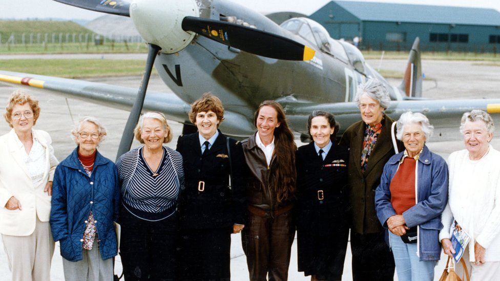 Former ATA pilots standing in front of a Spitfire - Frances Horsburgh, Maggie Frost, Peggy Lucas, Joy Lofthouse, Carolyn Grace (not Ata owns the Spitfire in The background), Diana Barnato Walker, Freydis Sharland, Ann Welch and Annette Hill.