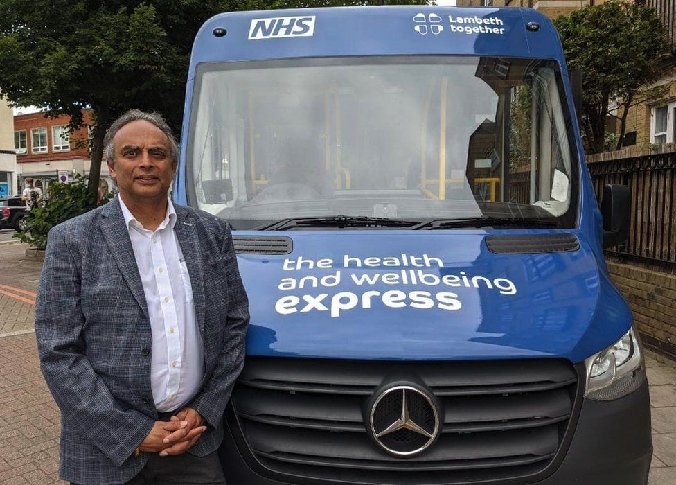 Ash Soni posing next to NHS bus