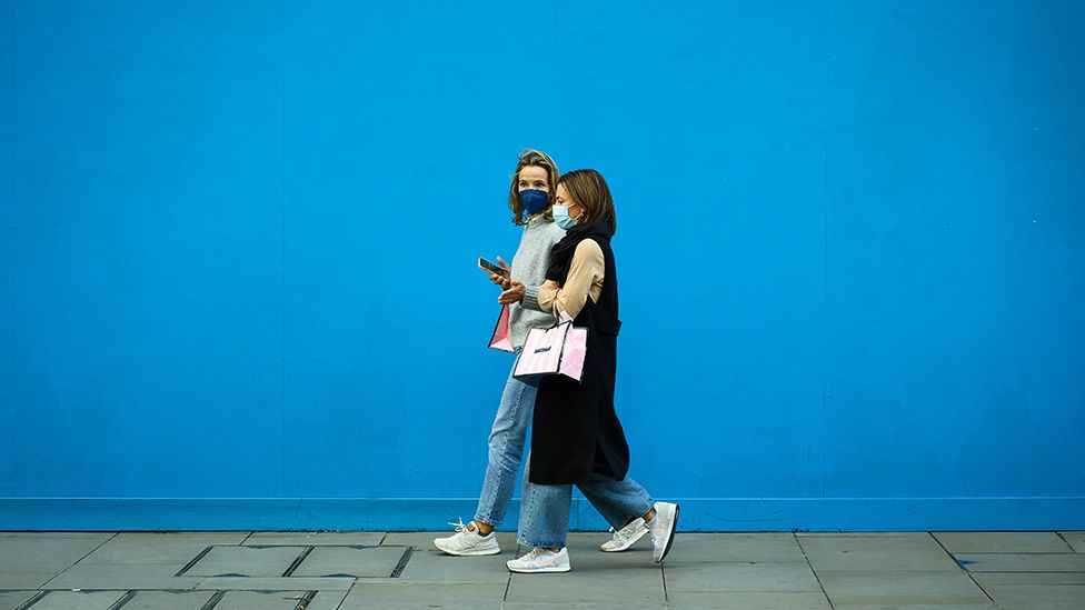 Two women wear protective facemasks as they walk in the Oxford Street retail district in London - October 20, 2021