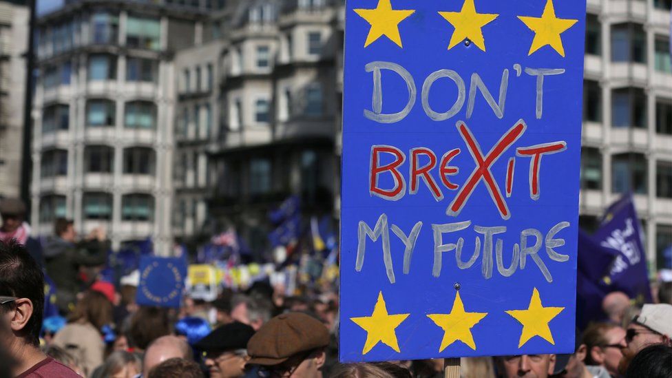 Demonstrators hold placards as they prepare to participate in an anti Brexit, pro-European Union (EU) march in London on 25 March 2017