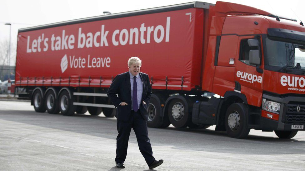 Boris Johnson walking in front of a branded lorry