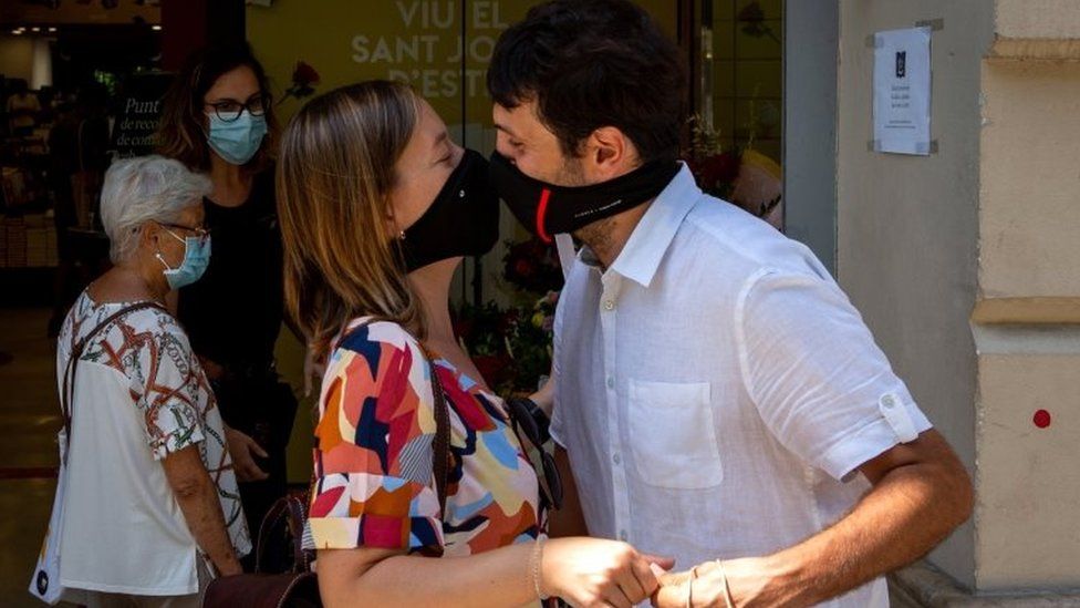 A couple wearing face masks kiss after giving each other books and roses during the Sant Jordi (St George) celebrations in Barcelona