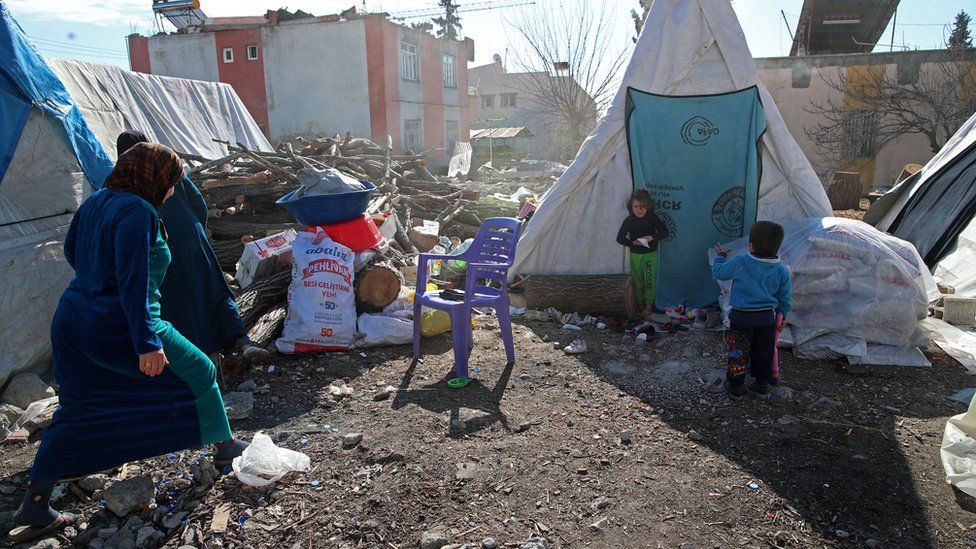 An earthquake victim family stands next to their tents following a powerful earthquake in Adiyaman, Turkey