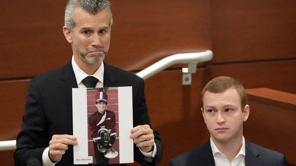 A man in court holds a photo of his son who was among those killed in a 2018 Parkland high school shooting.