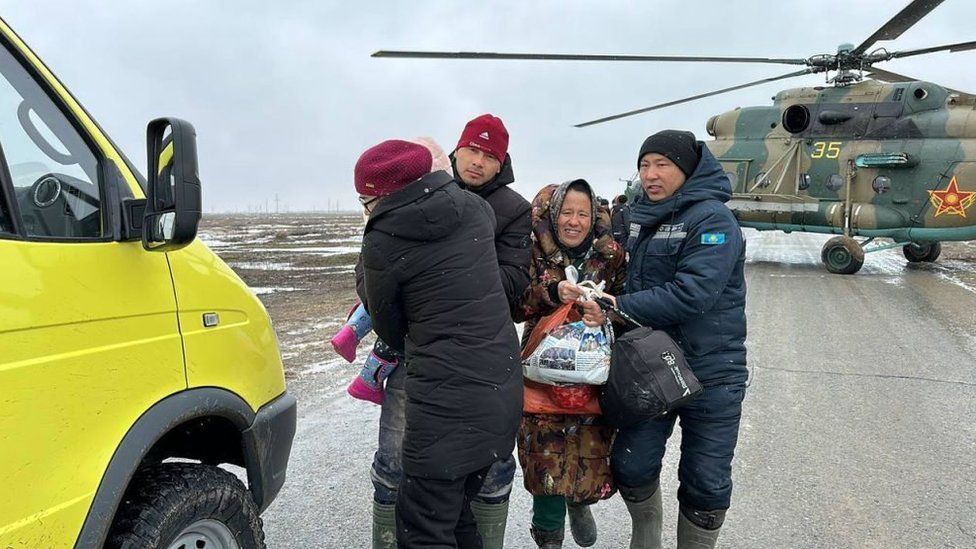 Rescue workers supporting a child and a woman walking away from a rescue helicopter in Kazakhstan