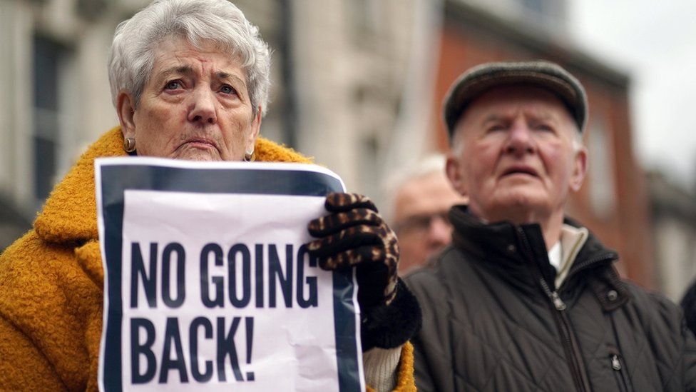 Woman holding sign saying 'no going back' - People taking part in a rally outside Omagh Courthouse to unite against paramilitary violence following the shooting of Detective Chief Inspector John Caldwell.