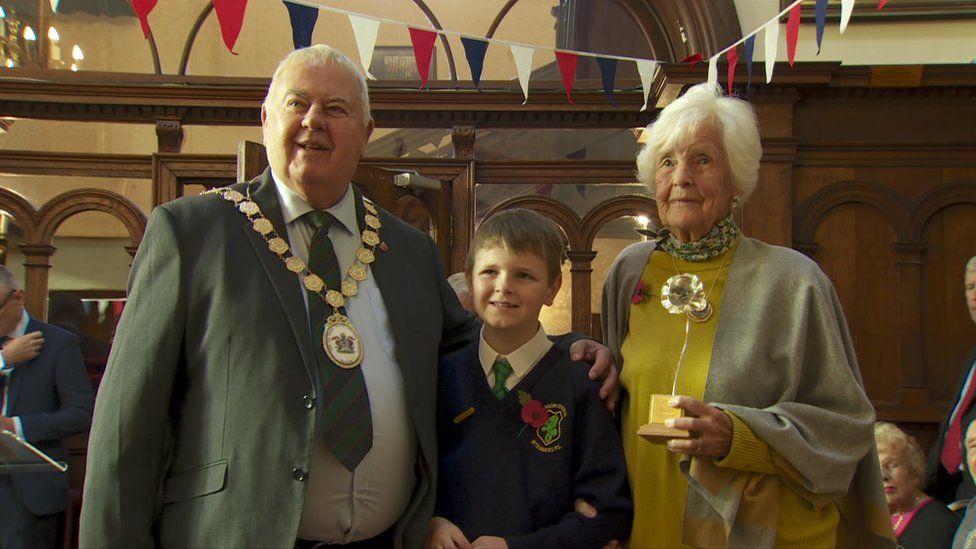 Maureen Lightbody, holding her silver poppy, with Mayor Bill Keery and a schoolboy from Bangor