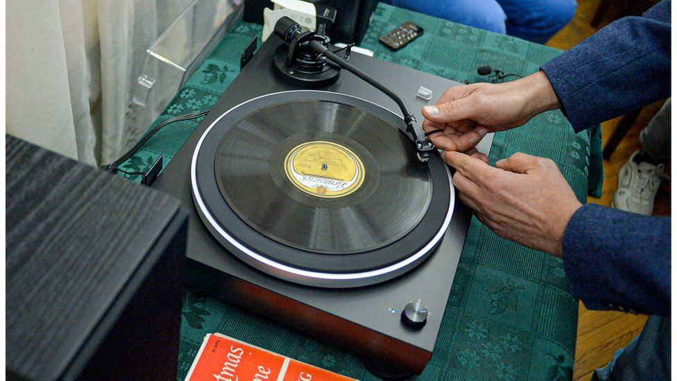 Hands set the needle of a record player