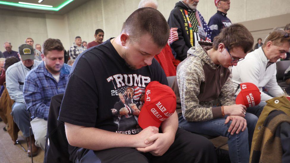 Trump supporters bow their heads in prayer at an Iowa campaign event