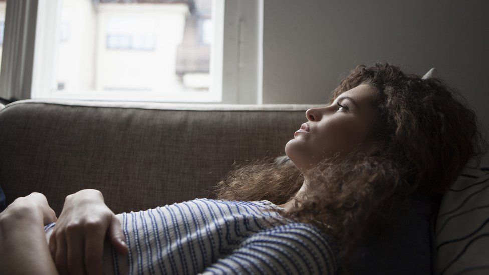 Woman lying on a sofa looking pensive