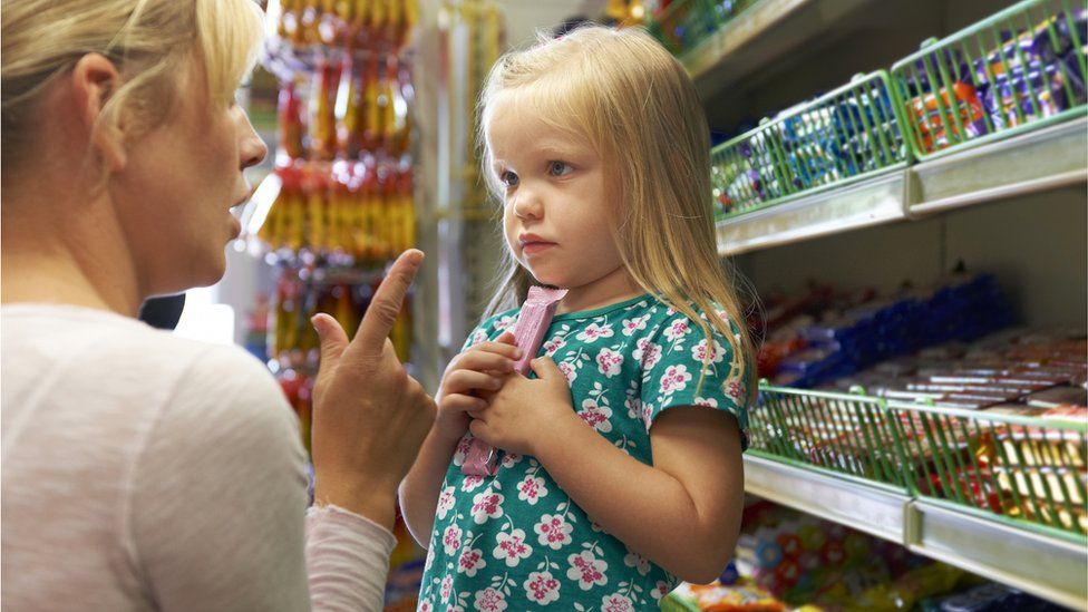 A child picking up chocolate from a supermarket shelf