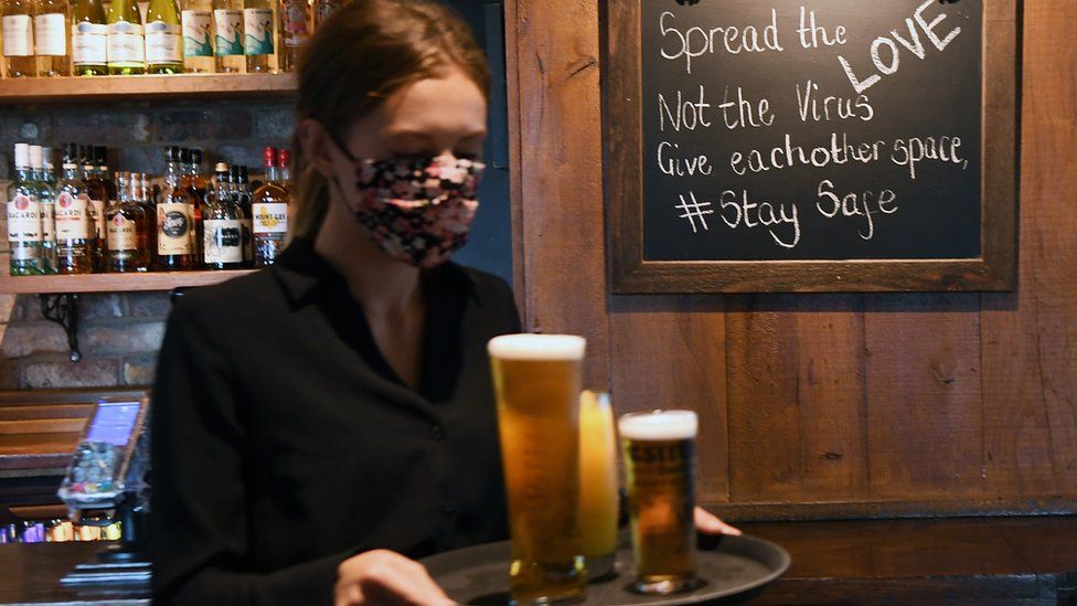 A staff member carries drinks to table at a pub in Chessington, Britain,