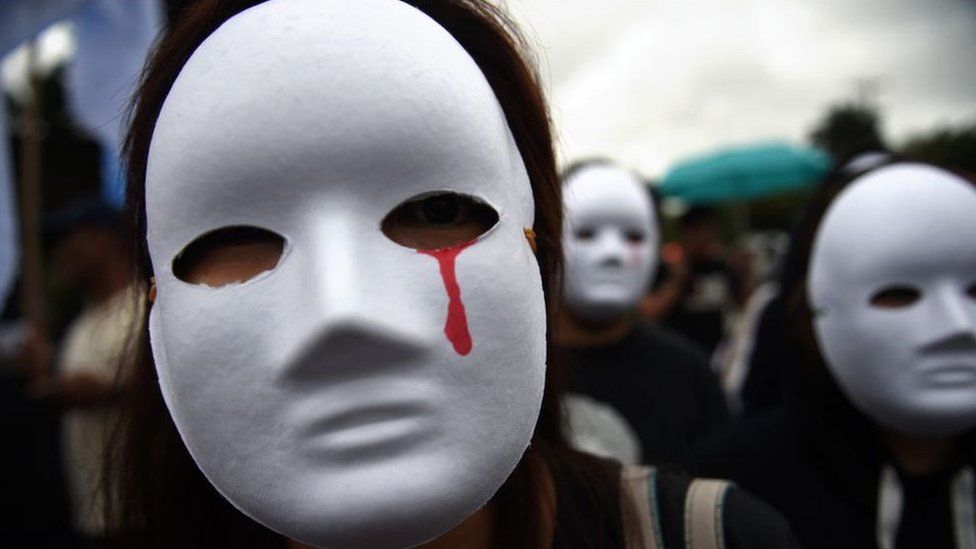 Protester against drug war killings in white mask