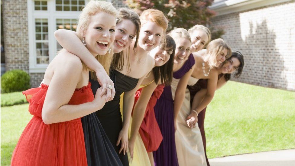 A group of female high school students outside in their prom dresses