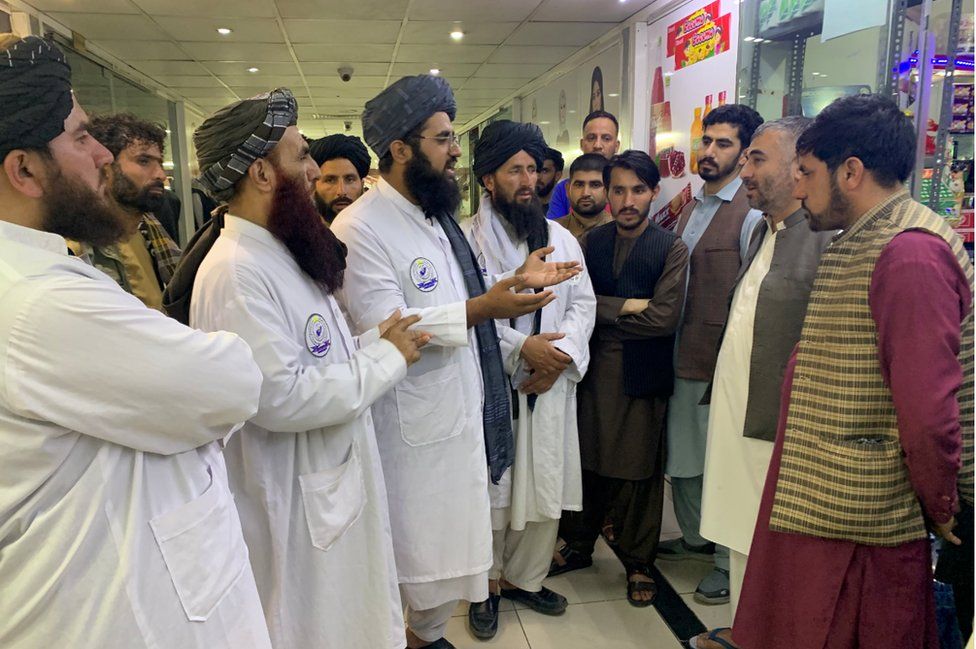 Maulvi Fatih and his officials talk to shop keepers and members of the public at a Kabul mall