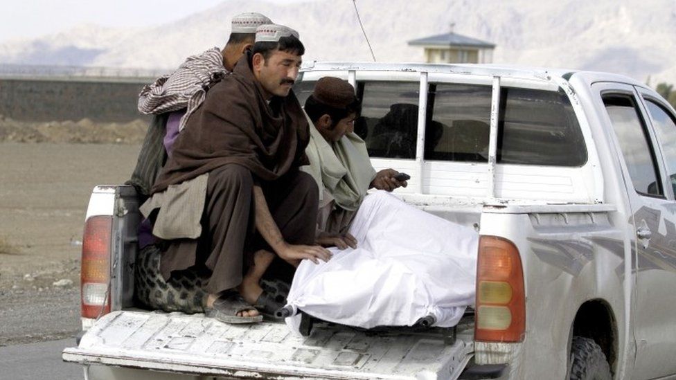 Afghan men move the body of a man after clashes between Taliban fighters and Afghan forces in Kandahar Airfield (09 December 2015)