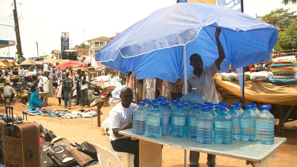 Men with water bottles in a market stall