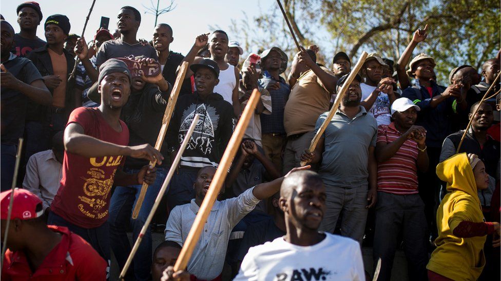 A group of Zulu men residing at the Jeppe Hostel shout and wave stick during a speech given by the Police Minister General Bheki Cele in JeppesTown, on September 3 in Johannesburg, 2019