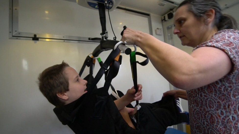 Adam, with his mother, in the Mobiloo hoist