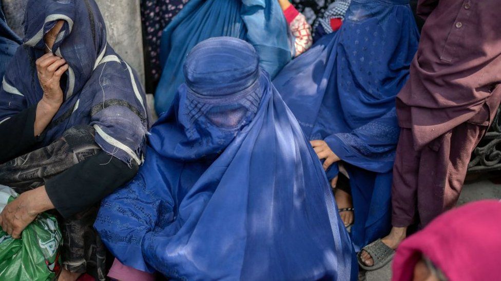 Women wait in front of a bank to withdraw money in Kabul.