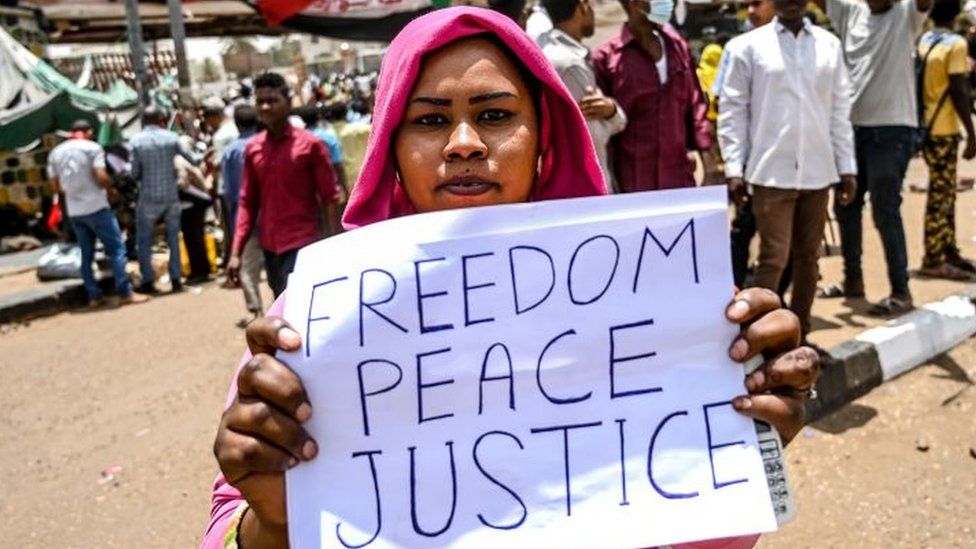 A Sudanese protestor holds a placard which reads 'Freedom Peace Justice' during a protest outside the army complex in the capital Khartoum on 18 April 2019.
