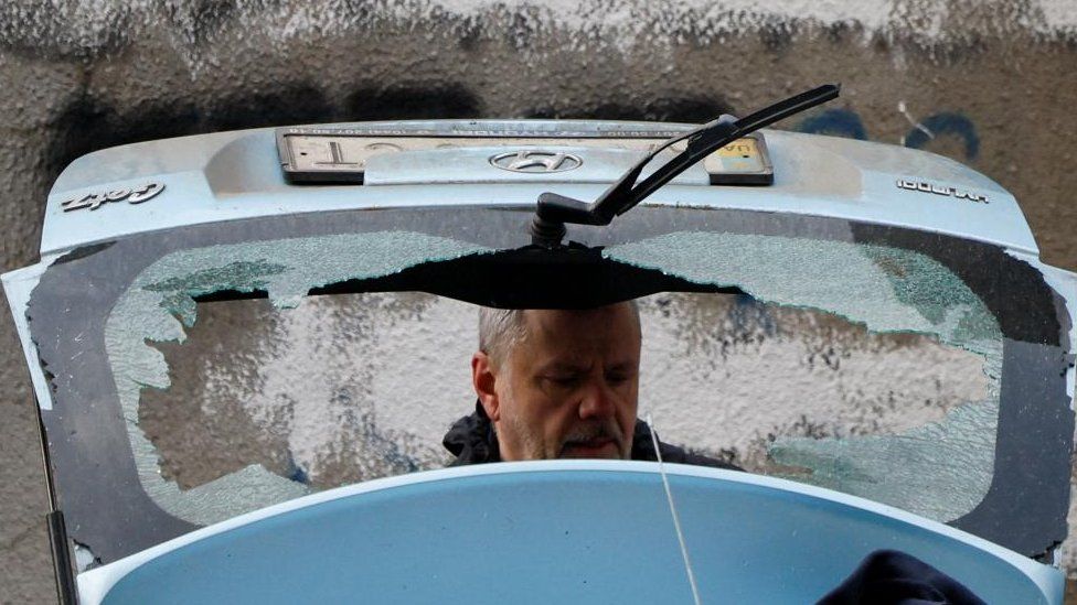 A man checks a damaged car at the site of a Russian missile strike in Kyiv