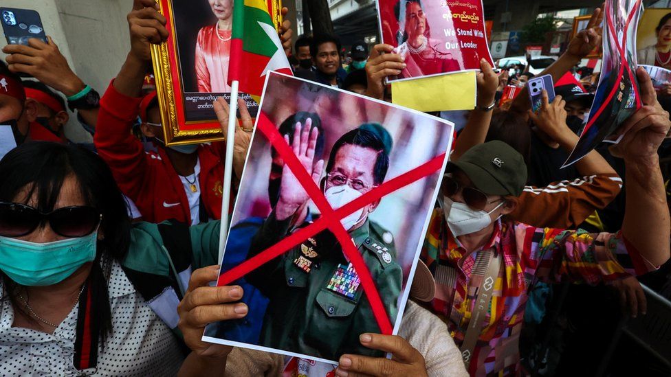 Протестующие держат фотографию командующего армией Мьянмы Мин Аунг Хлаинга с перечеркнутым лицом и фотографии Аунг Сан Су Чжи во время демонстрации, посвященной второй годовщине военного переворота в Мьянме в 2021 году, возле посольства Мьянмы в Бангкоке, Таиланд