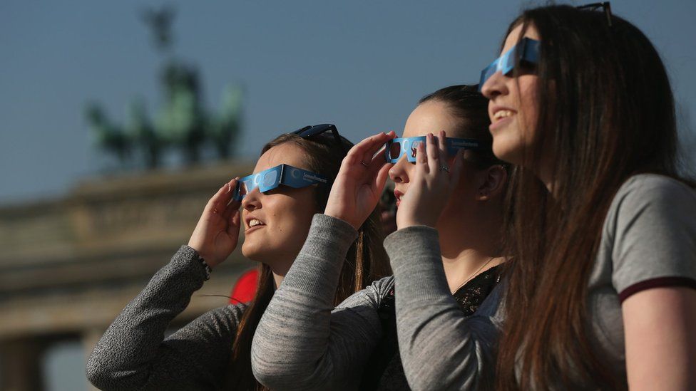 People use special glasses to look into the sky at a partial solar eclipse near the Brandenburg Gate on March 20, 2015 in Berlin