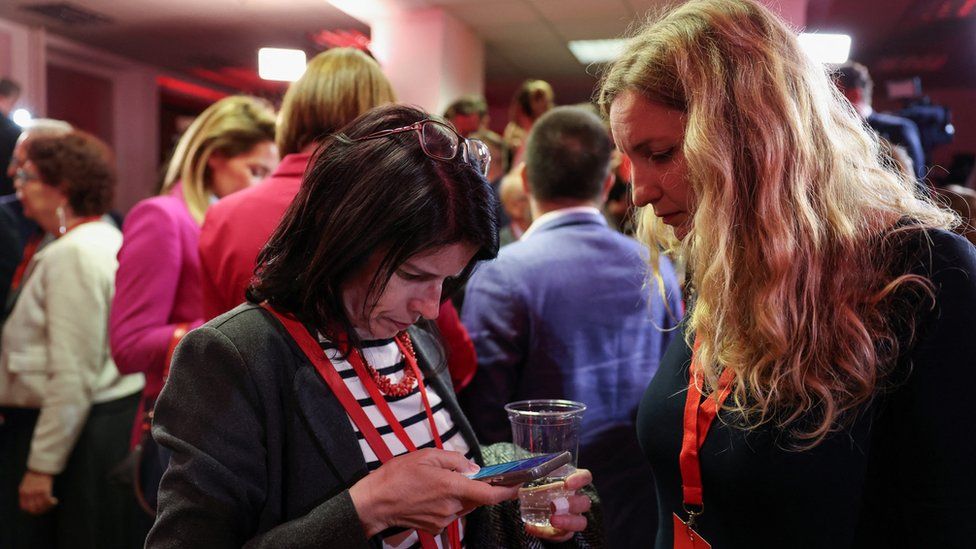 Members of the SDP check election results on a phone