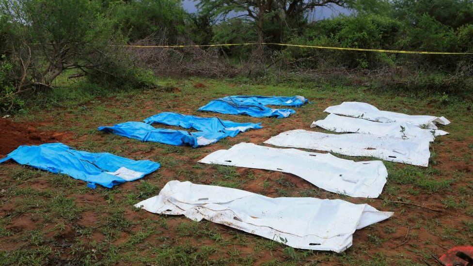 Body bags are seen arranged as forensic experts and homicide detectives exhume bodies