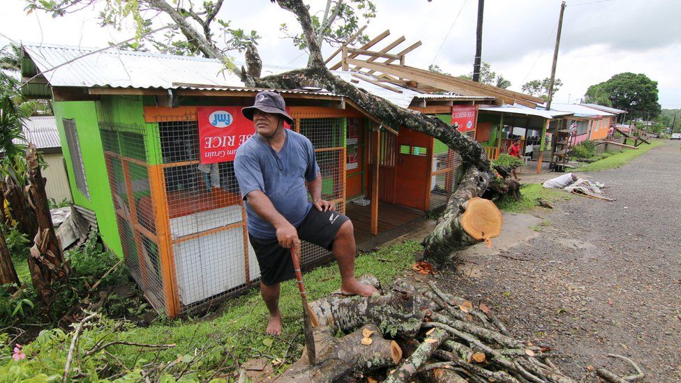 A man chops up a tree that hit his shop