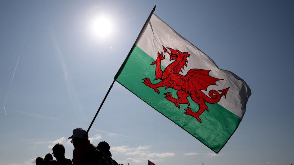 Wales flag being held up in front of the sun