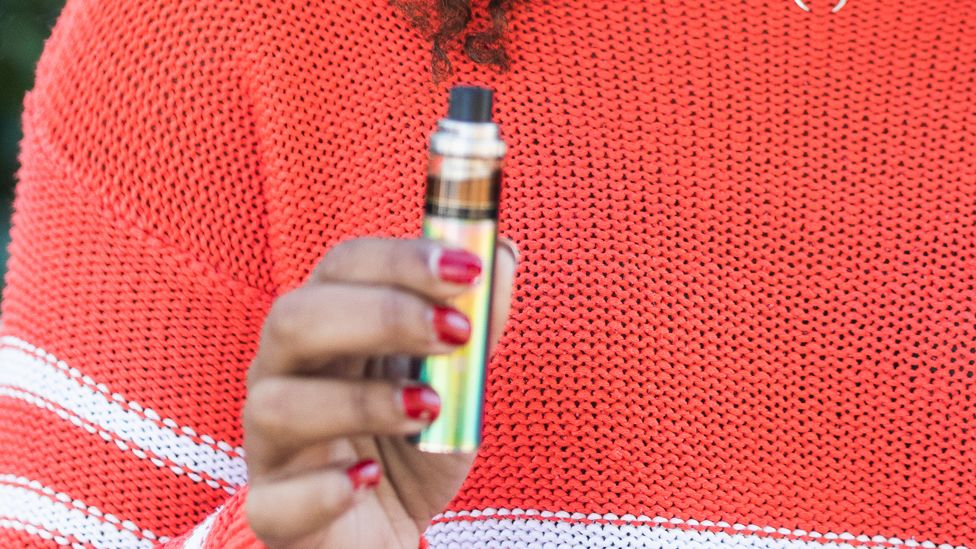 A woman with painted nails holding an e-cigarette