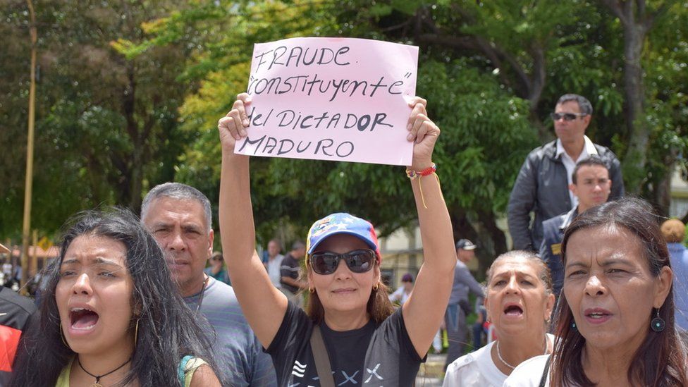 A woman holds up a sign at an anti-government protest in Merida reading: "Constituent fraud by dictator Maduro"