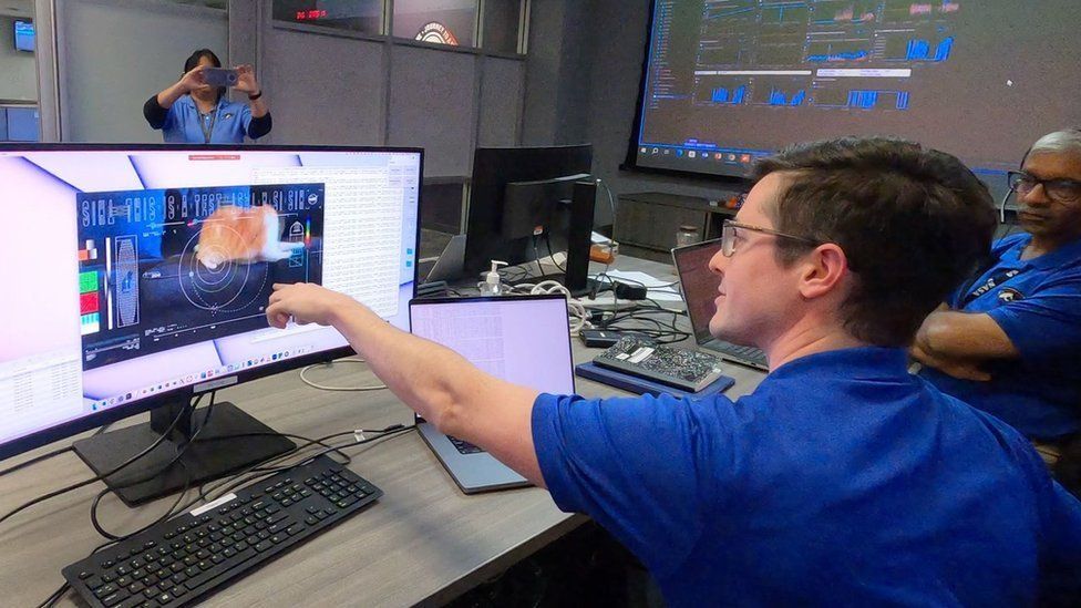 Nasa staff point at a video of the cat on their computer screens