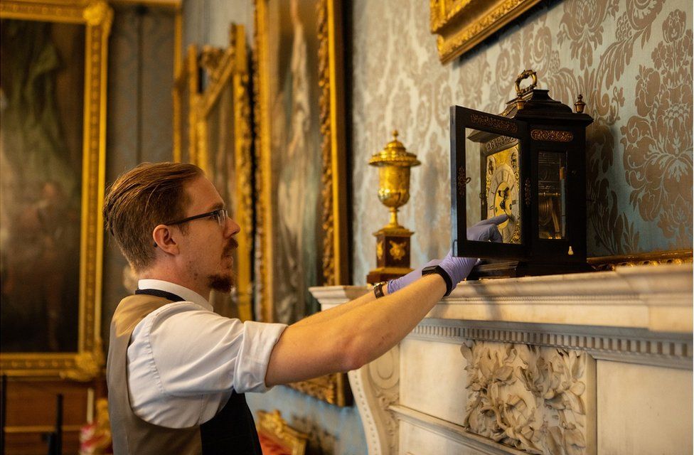 A close-up of Fjodor changing the time on a clock in a state apartment