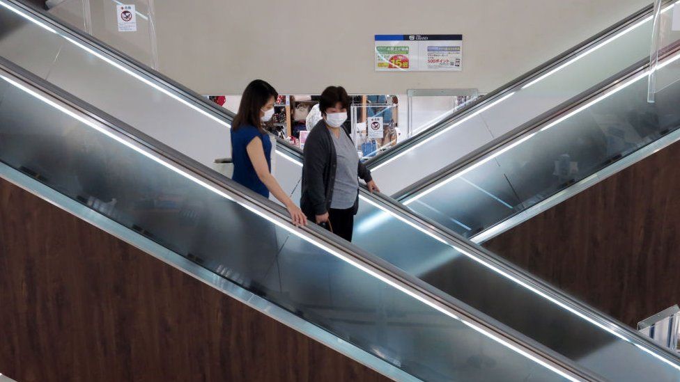 People wearing face masks on an escalator in a shopping centre in Japan.