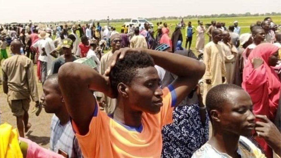 People watch as rescuers search for survivors in the River Niger after a boat capsized