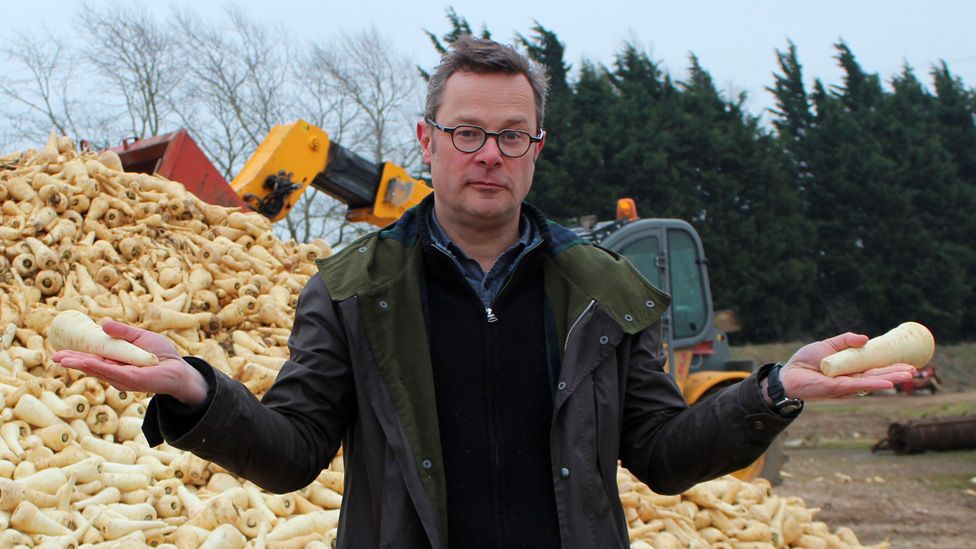 Hugh Fearnley-Whittingstall standing in front of a mountain of parsnips