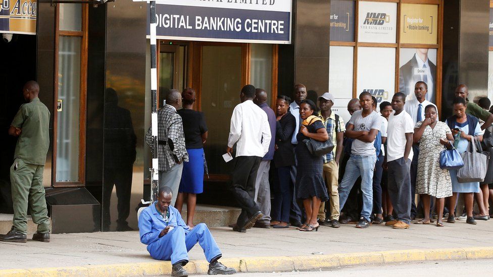 People queue to withdraw money outside a bank in Harare, Zimbabwe,