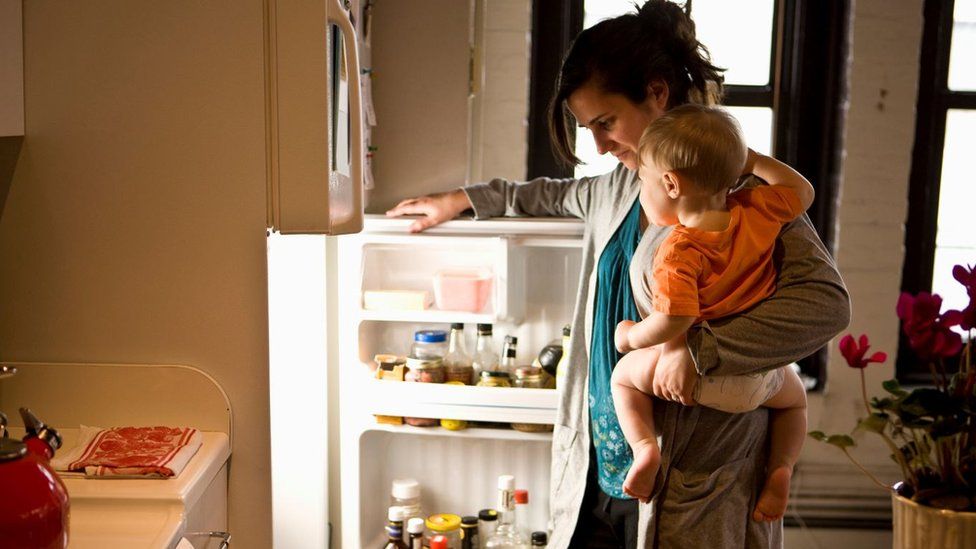 Woman with baby looks in fridge