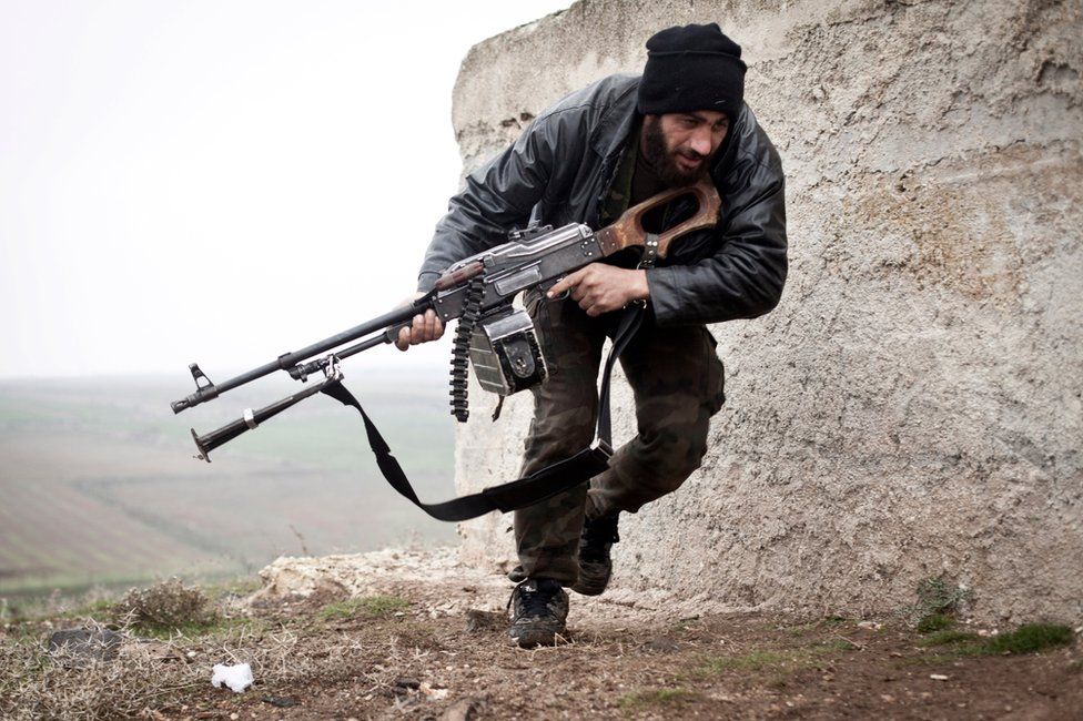 Сирийский повстанец укрывается во время боев с сирийской армией в Азазе, Сирия (17 декабря 2012 г.)