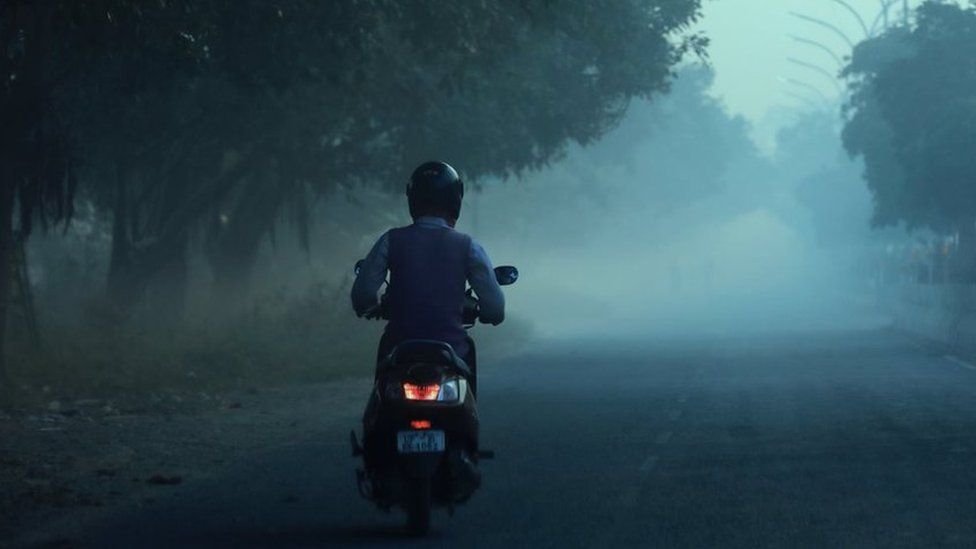A commuter going on his motorbike in smog