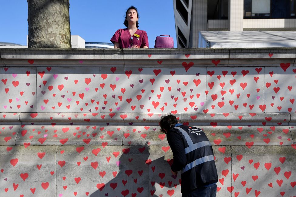 A health worker stands behind a wall painted in hearts, on 29 March 2021