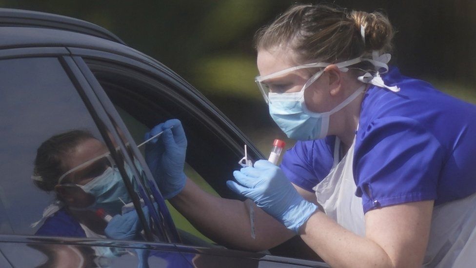 A medical worker swabs a motorist at a testing centre