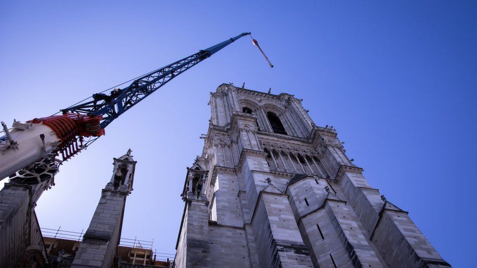 A crane looms over Notre-Dame cathedral in Paris