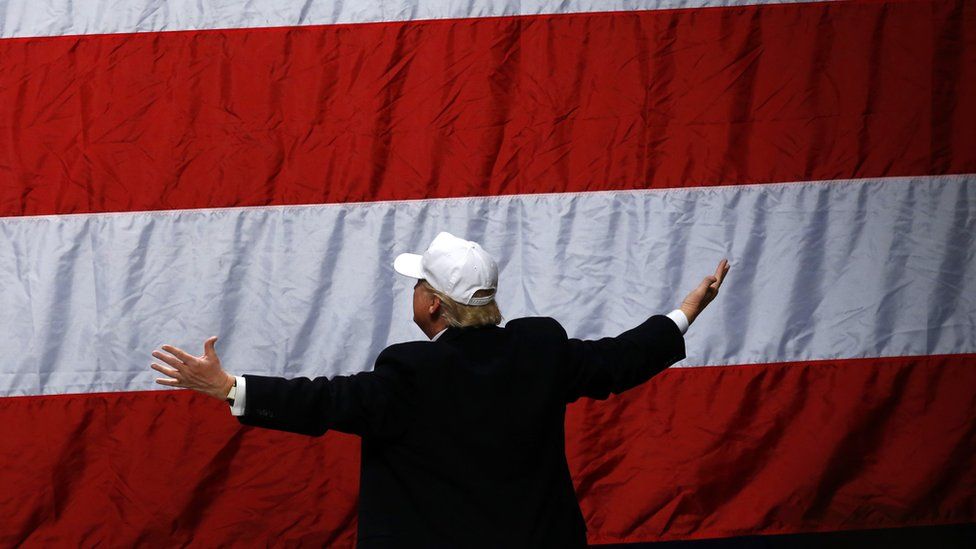 Donald Trump looks to the flag after he addressed supporters